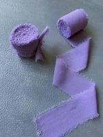 Два рулони фіолетової стрічки поруч із розкладеним фрагментом
