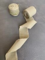 Два рулони бавовняної оливкової стрічки поруч, один із розгорнутим кінцем